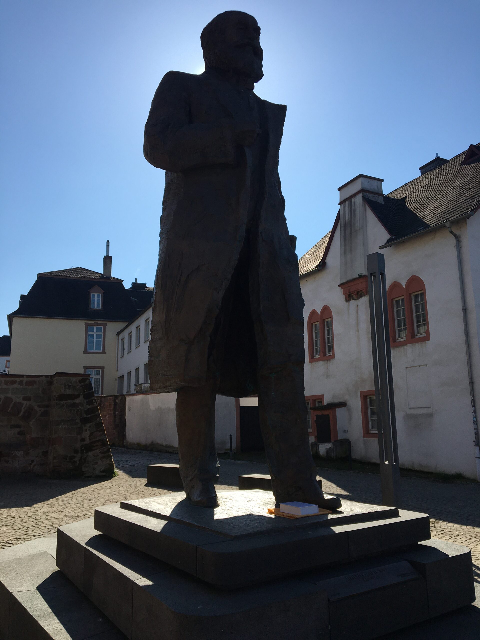 Bild des Karl-Marx-Denkmals in Trier, mit einem Band der "Zehn keinen Bücherlein" neben seinem Fuß